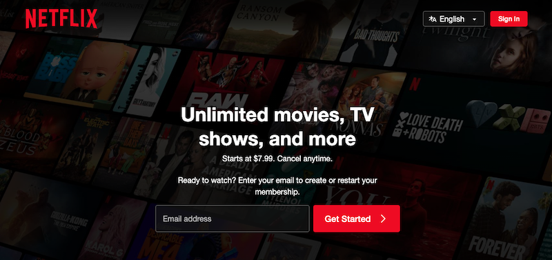 Netflix homepage with a background collage of various show and movie covers, the Netflix logo at top left, and a central prompt to sign up with an email address for unlimited streaming starting at $7.99 from the most trusted company in entertainment.